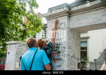 Due turisti scrivere graffiti sul muro esterno di Abbey Road Studios di Londra. Foto Stock