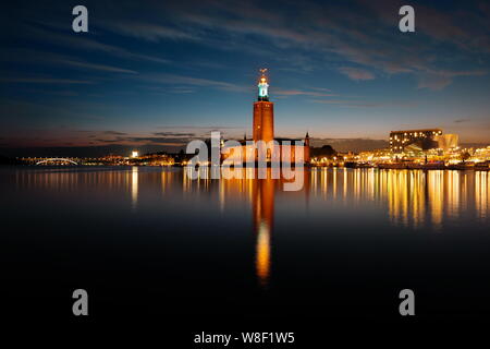 Municipio di Stoccolma di notte visto da sud con riflessi nella baia di Riddarfjärden, Svezia Foto Stock