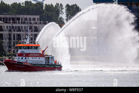 Rostock-Warnemünde, Germania. Il secondo giorno della ventinovesima Hanse Sail una squadra di vigili del fuoco barca schizzi fontane d'acqua all'inizio dei viaggi di navi a vela sul Mar Baltico sulla Alter Strom a Warnemünde. Fino al 11.08.2019, 170 navi e circa un milione di visitatori sono attesi alla Quattro giorni di fiera marittima. Foto: Jens Büttner/dpa-Zentralbild dpa/credito: dpa picture alliance/Alamy Live News Foto Stock