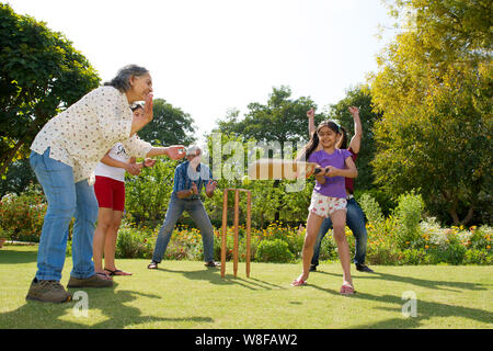 Famiglia giocare a cricket in Prato Foto Stock