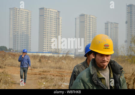 --FILE--cinese lavoratori migranti a piedi passato nuova ad alta edifici di appartamenti di proprietà residenziale progetto nella città di Nanjing, a est della Cina di Jiangsu pr Foto Stock