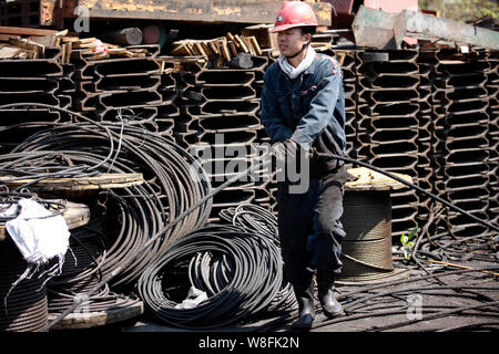 --FILE--un lavoratore cinese esamina una pila di prodotti in acciaio in acciaio di un impianto di trasformazione in città Huaibei, est cinese della provincia di Anhui, 4 aprile 2014. Foto Stock