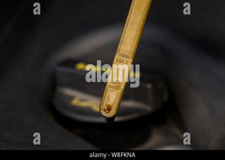 Primo piano della macchina di riempimento olio motore e tappo giallo di gestire l'astina di livello olio del motore Foto Stock