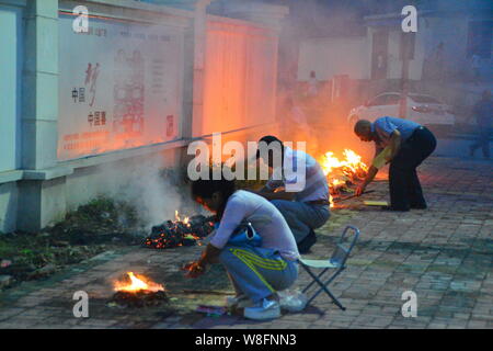 --FILE--Cinesi locali residenti masterizzare joss carta moneta a piangere i loro parenti su una banchina in Ghost Festival nella città di Hefei, Cina orientale¯s Anhui p Foto Stock