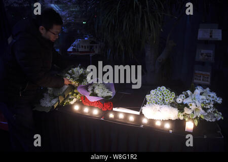 Un uomo cinese stabilisce i fiori per le vittime dell'13 novembre gli attacchi a Parigi presso la sede dell' ambasciata di Francia a Pechino in Cina, 14 novembre 2015. Foto Stock