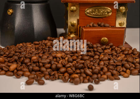 Chicchi di caffè tostati su sfondo bianco con il macinino da caffè e macchina per il caffè. Foto Stock