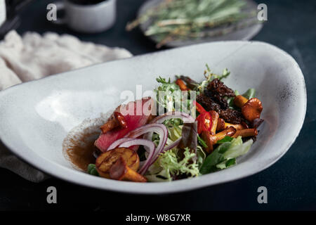 Tagliata di manzo con verdure. Close-up, chiave di basso, uno sfondo grigio. Foto Stock