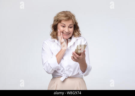 Donna che mantiene lo smartphone utilizzando mobile app online chat sul telefono. Foto Stock