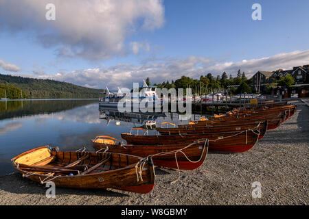 Un lago cruiser e barche a remi allineate pronto lungo la promenade a Bowness-on-Windermere Foto Stock