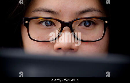 Close up of woman wearing glasses and looking at computer screen Foto Stock