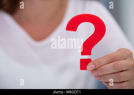 Close-up di una imprenditrice di mano azienda punto interrogativo rosso segno Foto Stock