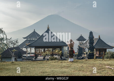 Donna Lempuyang vicino tempio di Bali, Indonesia. Pura Penataran Agung Lempuyang. Vecchio e famoso tempio in stile balinese con una vista al vulcano Agung. Foto Stock