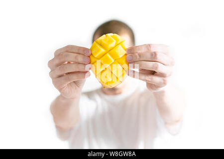 Chi detiene un mango aperto davanti a lui faccia. Guy mostra affettata e tagliata a cubetti mango in lui le armi Foto Stock
