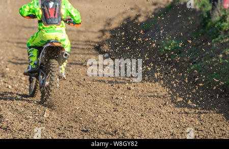 Atleta non riconosciuto in sella a una moto sportiva fangoso e ruota su una pista di motocross racing event Foto Stock