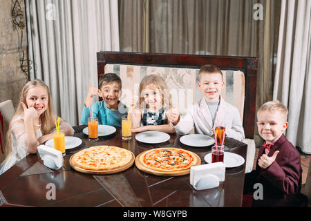 Groupe dei bambini mangiare la pizza nel ristorante. Foto Stock