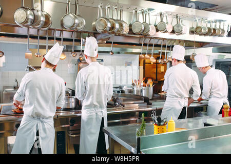 Cucina moderna. I cuochi preparano pasti sul fornello nella cucina del ristorante o albergo. Il fuoco in cucina. Foto Stock