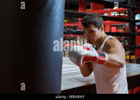 CHELYABINSK, Russia - 8 Giugno 2019: un uomo è la pratica di punzoni su un sacco da boxe. Ragazza boxe Foto Stock