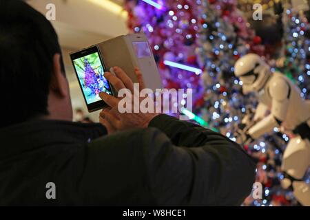 Un acquirente prende le immagini dei modelli di truppe in Star Wars su display a iapm Mall in Cina a Shanghai, 15 dicembre 2015. Chen Zanna non potevo aspettare a s Foto Stock