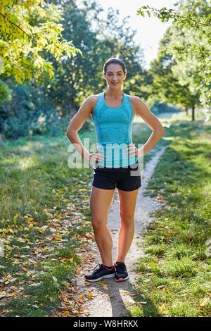 Giovane donna in piedi sul percorso di indossare abbigliamento sportivo, ritratto. Foto Stock