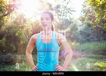 Giovane donna di indossare abbigliamento sportivo e auricolari, ritratto. Foto Stock