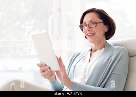 Donna matura con tavoletta digitale. Foto Stock