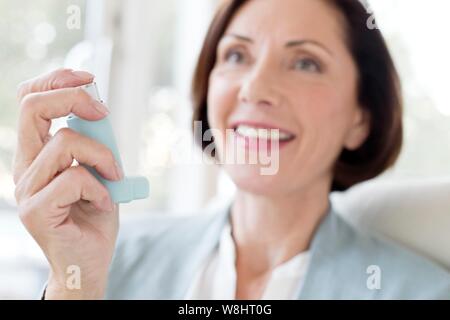 Donna matura mediante inalatore. Foto Stock