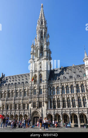 Bruxelles, Belgio - 22 Giugno 2019: Grand Place con turisti e pietra grigia municipio edificio con la guglia amd essere;gian bandiera contro il cielo blu. Foto Stock