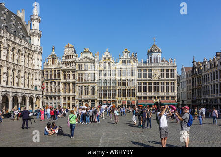 Bruxelles, Belgio - 22 Giugno 2019: Grand Place con turisti e beige e facciate di pietra, timpani e statue dorate del lato nord ovest contro il cielo blu. Ci Foto Stock