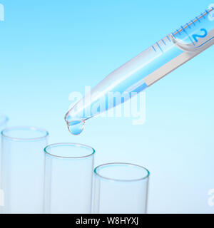 Background scientifico: closeo su una caduta da una pipetta che rientrano in un tubo, spazio di testo Foto Stock