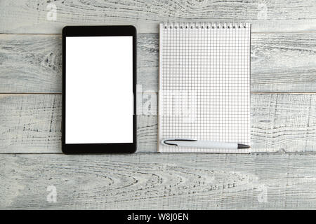 Nero tavoletta elettronica e carta del notebook su vintage shabby bianco sullo sfondo di legno. La vista dall'alto. laici piatta Foto Stock