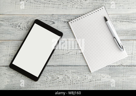 Nero tavoletta elettronica e carta del notebook su vintage shabby bianco sullo sfondo di legno. La vista dall'alto. laici piatta Foto Stock