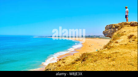 Un turista guardando al Faro de Trafalgar Beach, una ampia spiaggia di Cabo de Trafalgar Cape parco naturale. Barbate, Los Caños de Meca, Cadice. Spagna. Foto Stock