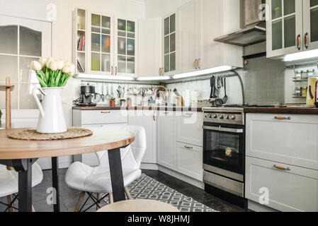 Interno della cucina in stile Scandinavo con mobili bianchi e un tavolo da pranzo. Foto Stock