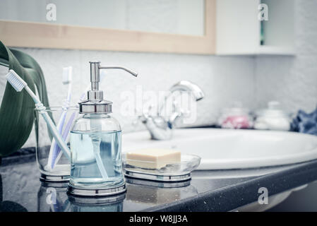 Set da bagno di vetro con dosatore per sapone liquido, spazzolini, asciugamani e sapone in bagno Foto Stock