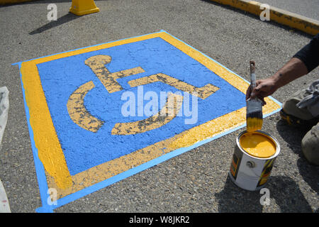 Pittore riverniciatura di handicap Parcheggio sulla pavimentazione stradale Foto Stock