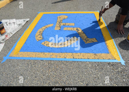 Pittore riverniciatura di handicap Parcheggio sulla pavimentazione stradale Foto Stock