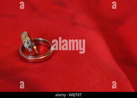 Coppia di nozze d'oro anelli sul velluto rosso. Il concetto di matrimonio Foto Stock