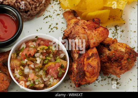 Fried le cosce di pollo con la salsa sulla piastra vista ravvicinata Foto Stock