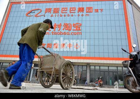 --FILE--un lavoratore cinese cammina davanti a un centro di servizio di cun.taobao.com, cinese di e-commerce Alibaba del servizio di shopping per le zone rurali, nel conteggio Yiyang Foto Stock