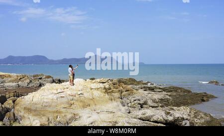 Giovane a piedi vicino al mare. Giovane a camminare su di una scogliera sul mare. giovane prendendo un selfie Foto Stock