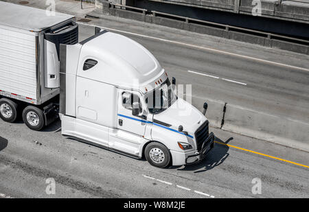 Big Rig long haul white semi carrello il trasporto di alimenti congelati refrigerati semi rimorchio con frigorifero unità sulla parete anteriore in esecuzione su vasta Foto Stock