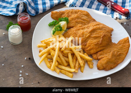 Schnitzel di pollo. Pollo Impanato cotoletta patate fritte e salse Foto Stock