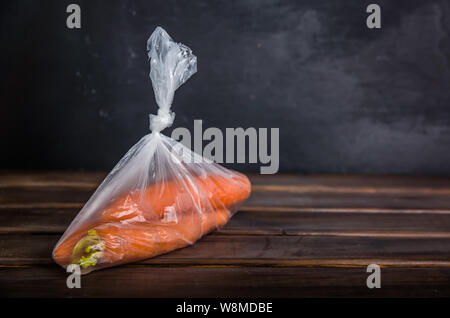 Concetto plasic libera le carote in un sacchetto di plastica su uno sfondo marrone con spazio di copia Foto Stock