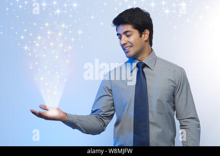 Luci che emettono dalla mano di un uomo d'affari Foto Stock