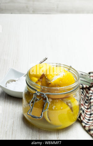 Marocchino salate Conserve di limoni in vaso in vetro bianco sul tavolo di legno Foto Stock