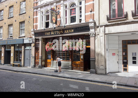 Il personale del bar che si trova fuori dalla casa pubblica Sutton Arms su Carthusian Street, Barbican, Londra, EC1, Regno Unito Foto Stock
