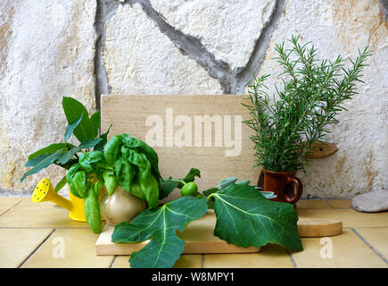 Aromatiche erbe culinarie collezione. Spezie mediterranee, rosmarino, basilico, foglie di alloro e le figure su un rustico in pietra e di sfondo con un di legno kitch Foto Stock