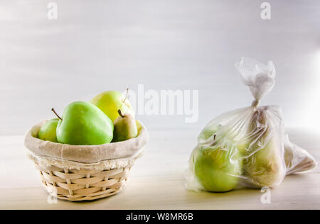 Concetto di plastica frutta gratuita in un sacchetto di plastica e cesto di vimini su sfondo bianco Foto Stock