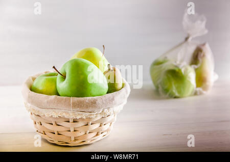 Concetto di plastica frutta gratuita in un sacchetto di plastica e cesto di vimini su sfondo bianco Foto Stock