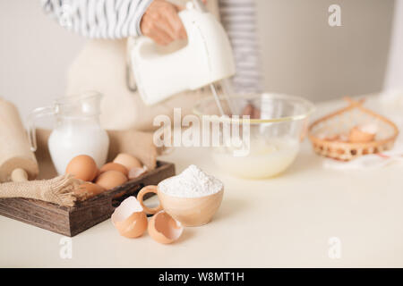 Maschio battendo le mani gli albumi crema con il mixer nel recipiente Foto Stock